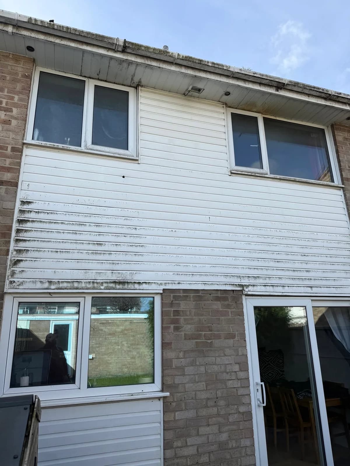 White exterior cladding with dark dirt and staining before cleaning