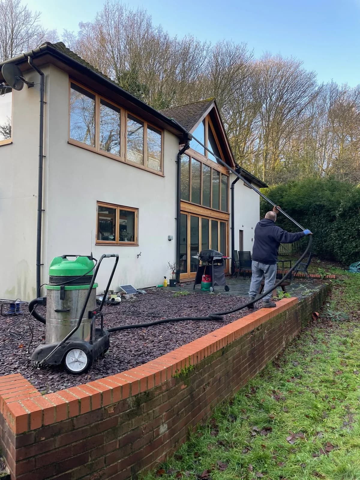 Our operative using a gutter vacuum and long-reach pole beside a two-storey property